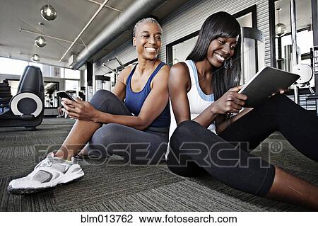 Stock Image - Women using digital tablet in health club. Fotosearch