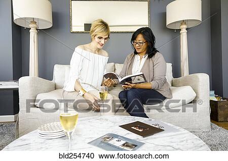 Stock Image - Women with champagne reading book. Fotosearch