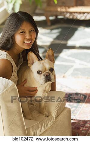 Stock Image - Asian woman petting dog. Fotosearch