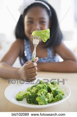 Stock Photo - Black girl eating broccoli. Fotosearch