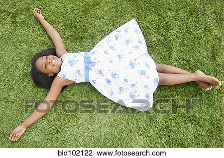 Stock Image - Black girl laying in grass. Fotosearch
