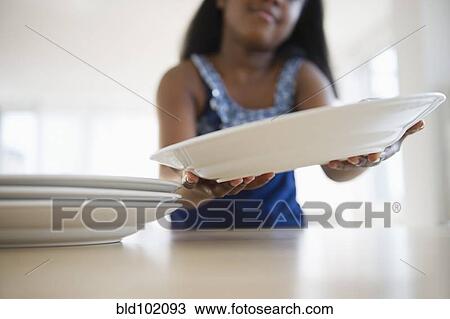 Stock Image - Black girl setting the table. Fotosearch