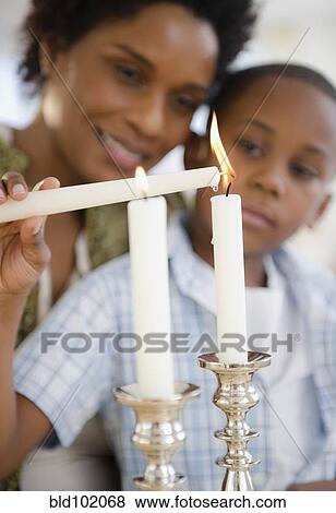 Stock Photo - Black mother and son lighting candles together. Fotosearch