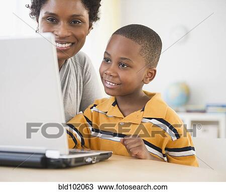 Stock Image - Black mother and son using laptop together. Fotosearch