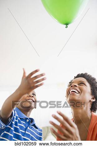 Stock Photo - Black mother and son watching floating balloon. Fotosearch