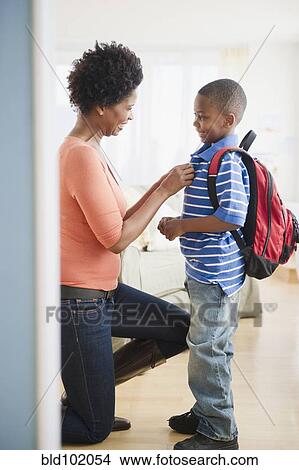 Picture - Black mother buttoning son's shirt. Fotosearch