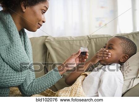 Stock Photograph - Black mother giving son cough syrup. Fotosearch