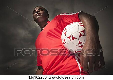 Black soccer player holding ball View Large Photo Image Stock Image - Black soccer player holding ball. Fotosearch