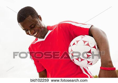 Stock Photo - Black soccer player holding ball. Fotosearch