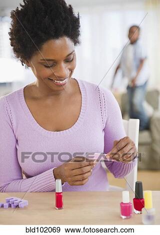 Stock Photo - Black woman giving herself a manicure. Fotosearch