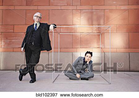 Stock Photo - Businessman standing next to co-worker in box. Fotosearch