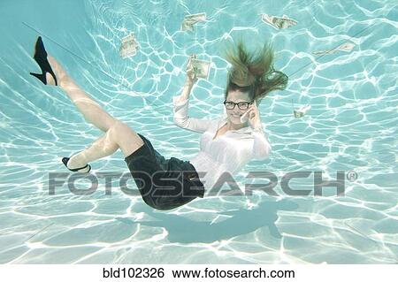 Stock Photograph - Caucasian businesswoman reaching for money underwater. Fotosearch