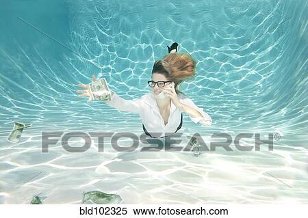 Stock Photography - Caucasian businesswoman reaching for money underwater. Fotosearch