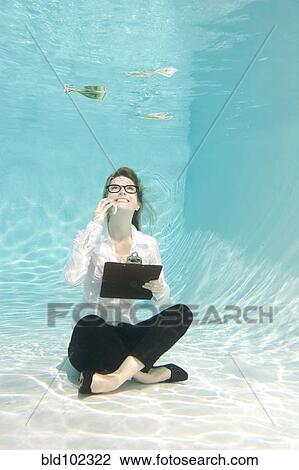 Stock Image - Caucasian businesswoman sitting underwater. Fotosearch