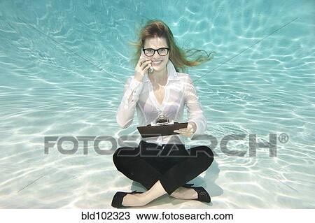 Stock Image - Caucasian businesswoman sitting underwater. Fotosearch