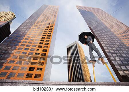 Stock Photo - Caucasian businesswoman walking on stilts in urban environment. Fotosearch