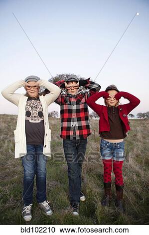 Stock Image - Caucasian children making faces with their hands. Fotosearch