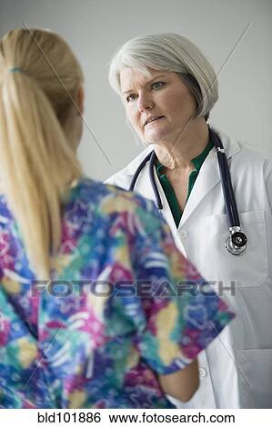 Stock Photograph - Caucasian doctor talking to nurse. Fotosearch