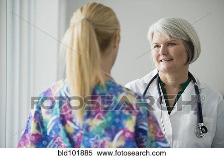Stock Photography - Caucasian doctor talking to nurse. Fotosearch