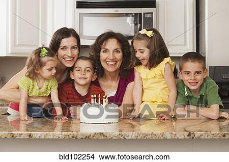Picture - Caucasian family in kitchen with birthday cake. Fotosearch