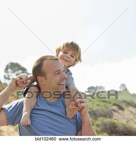 Stock Image - Caucasian father carrying son on shoulders. Fotosearch