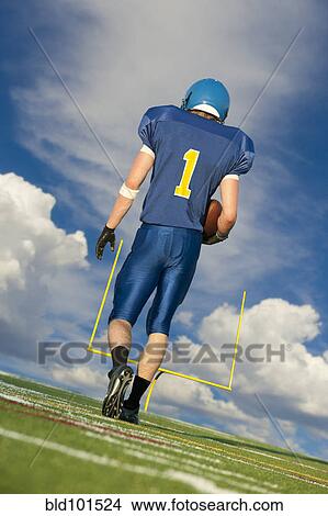 Picture - Caucasian football player carrying football. Fotosearch