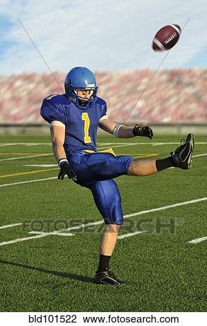 Stock Image - Caucasian football player kicking football. Fotosearch