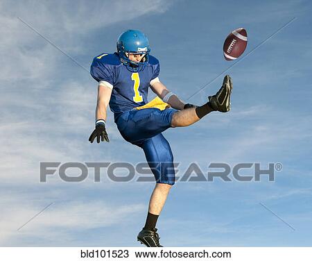 Stock Image - Caucasian football player kicking football. Fotosearch