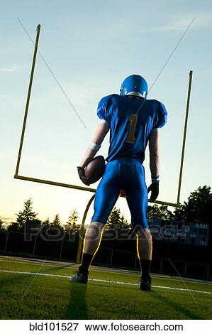 Stock Photo - Caucasian football player standing with football. Fotosearch