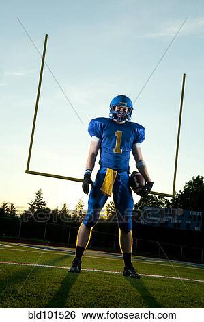 Stock Photograph - Caucasian football player standing with football. Fotosearch