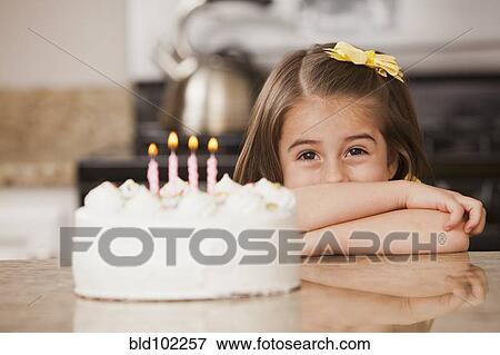 Stock Photo - Caucasian girl looking at birthday cake. Fotosearch