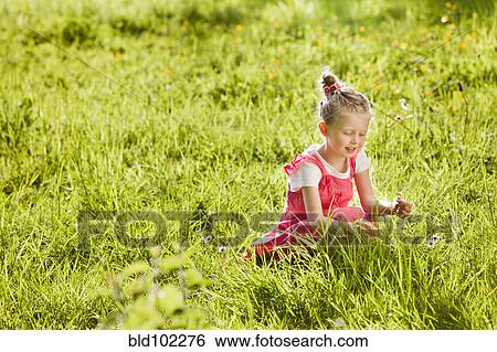 Stock Photograph - Caucasian girl picking flowers in field. Fotosearch