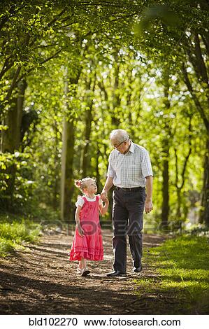 Stock Image - Caucasian grandfather and granddaughter walking in woods. Fotosearch