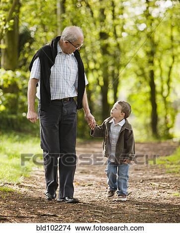 Picture - Caucasian grandfather and grandson walking in woods. Fotosearch