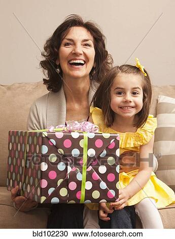 Stock Image - Caucasian grandmother and granddaughter holding gift. Fotosearch