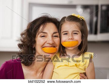 Stock Image - Caucasian grandmother and granddaughter eating fruit. Fotosearch