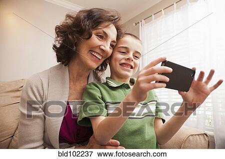 Caucasian grandmother and grandson looking at cell phone View Large Photo Image Stock Photo - Caucasian grandmother and grandson looking at cell phone. Fotosearch