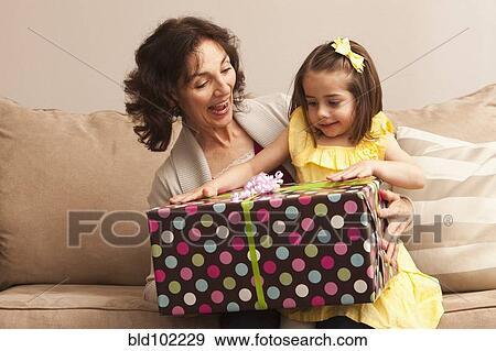 Stock Photo - Caucasian grandmother giving granddaughter gift. Fotosearch