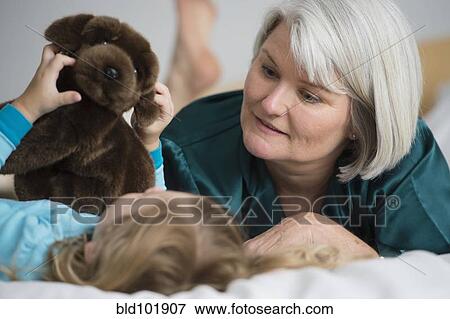 Caucasian grandmother laying on bed with granddaughter View Large Photo Image Stock Photo - Caucasian grandmother laying on bed with granddaughter. Fotosearch