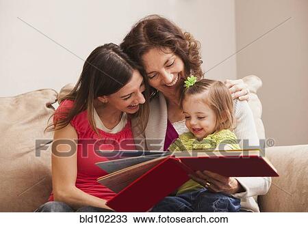 Stock Image - Caucasian grandmother, mother and daughter reading a book. Fotosearch