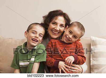 Stock Image - Caucasian grandmother sitting with grandsons. Fotosearch
