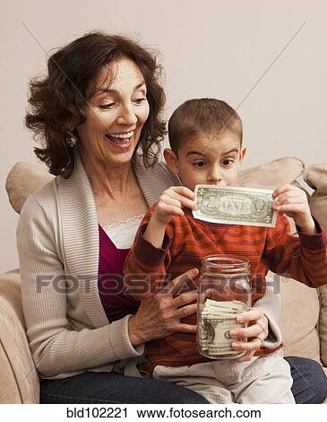 Caucasian grandmother watching grandson putting money in jar View Large Photo Image Stock Image - Caucasian grandmother watching grandson putting money in jar. Fotosearch