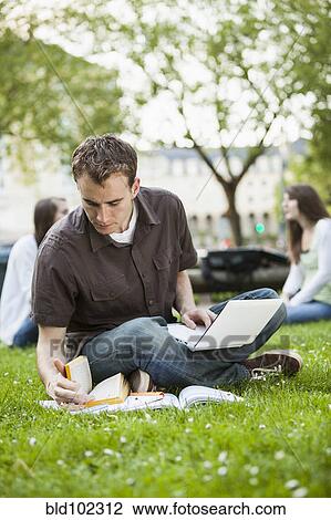 Stock Image - Caucasian man studying in grass. Fotosearch