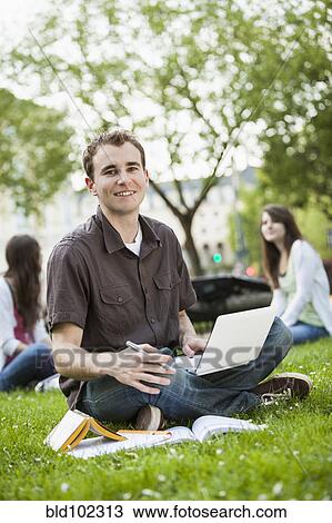 Stock Image - Caucasian man studying in grass. Fotosearch