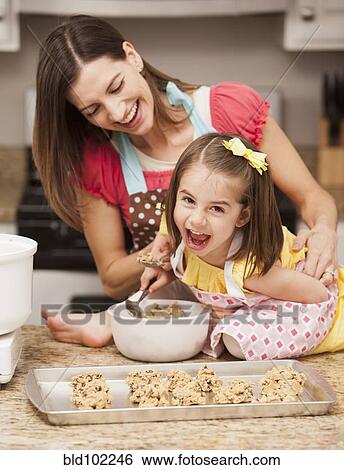Stock Photograph - Caucasian mother and daughter baking cookies. Fotosearch