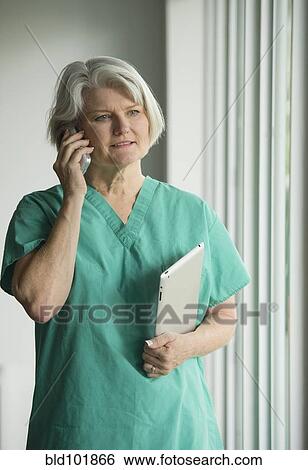 Stock Photograph - Caucasian surgeon in scrubs using cell phone. Fotosearch