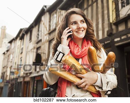 Stock Photo - Caucasian woman carrying bread and talking on cell phone. Fotosearch