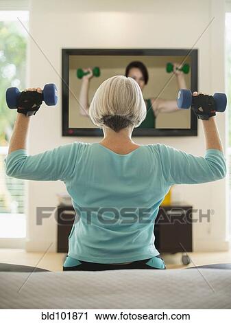 Stock Image - Caucasian woman exercising with hand weights. Fotosearch