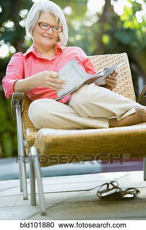 Caucasian woman reading magazine outdoors View Large Photo Image Stock Image - Caucasian woman reading magazine outdoors. Fotosearch