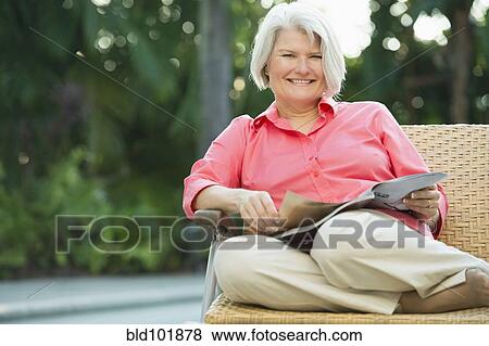 Stock Photo - Caucasian woman reading magazine outdoors. Fotosearch